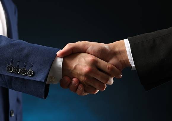 Business partners shaking hands on dark blue background, closeup